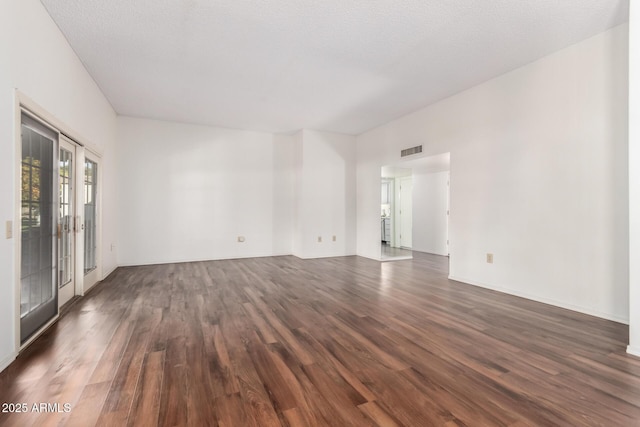 unfurnished room with dark wood-type flooring, a textured ceiling, and french doors