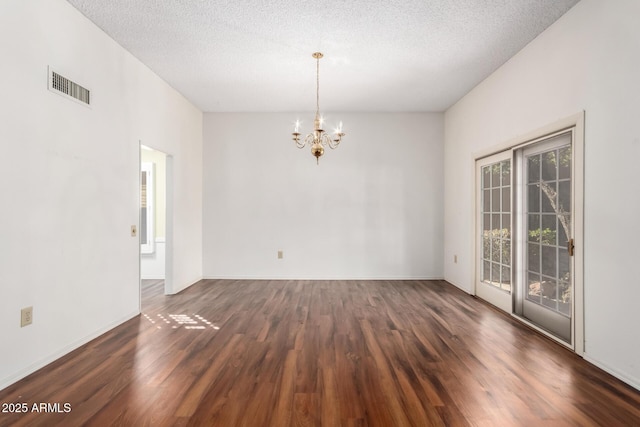 empty room featuring a textured ceiling, dark hardwood / wood-style floors, and a notable chandelier