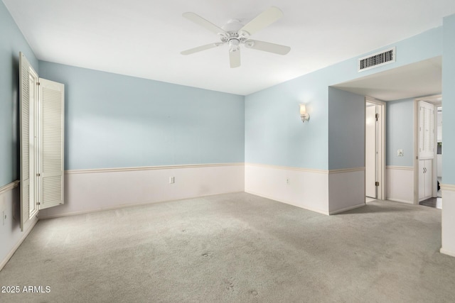 empty room featuring ceiling fan and light colored carpet