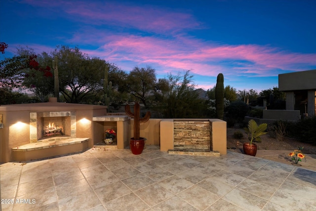 patio terrace at dusk with an outdoor stone fireplace