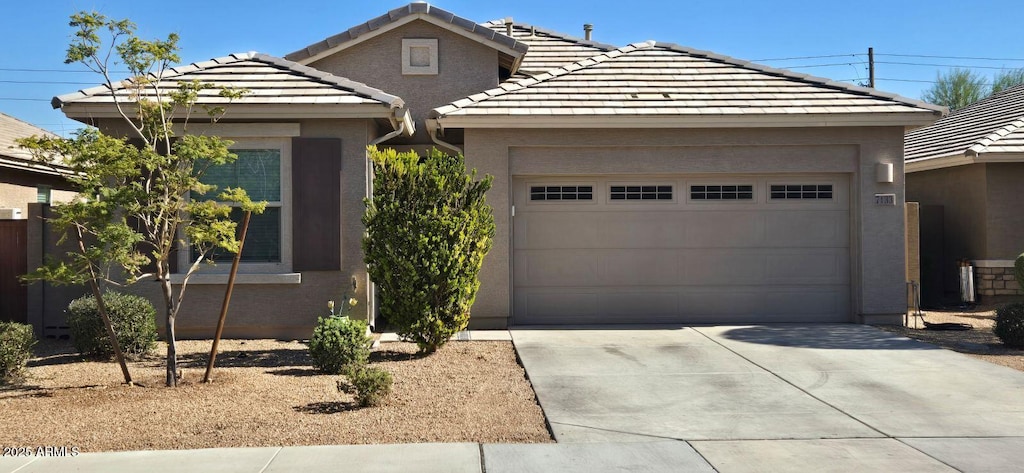 single story home with concrete driveway, a tiled roof, an attached garage, and stucco siding