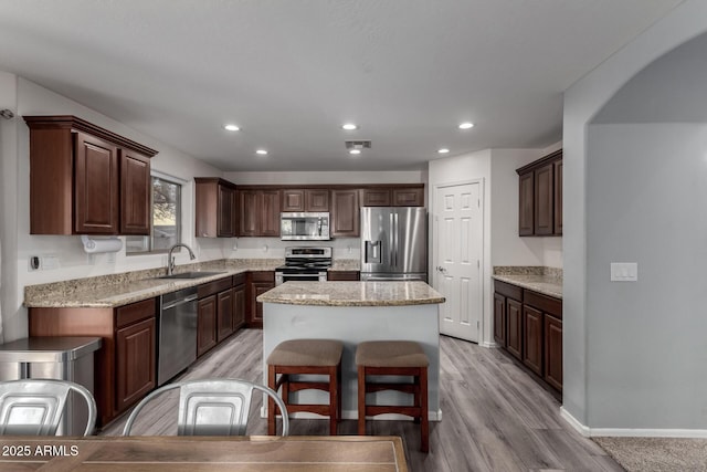 kitchen with a kitchen island, appliances with stainless steel finishes, light hardwood / wood-style floors, and dark brown cabinets