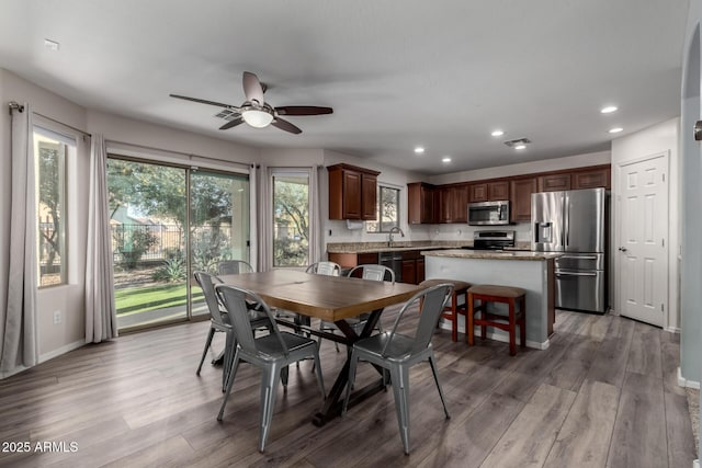 dining room featuring light wood-type flooring, ceiling fan, a wealth of natural light, and sink