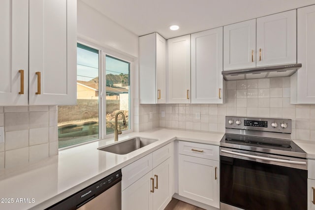 kitchen featuring light countertops, a sink, white cabinetry, appliances with stainless steel finishes, and under cabinet range hood