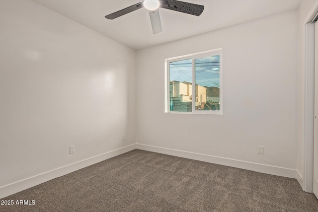 unfurnished room featuring baseboards, dark colored carpet, and a ceiling fan
