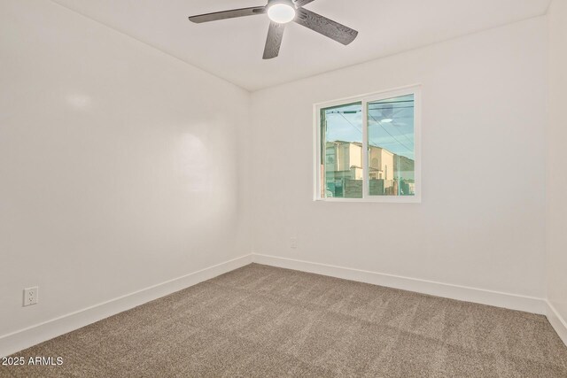 carpeted spare room with baseboards and a ceiling fan