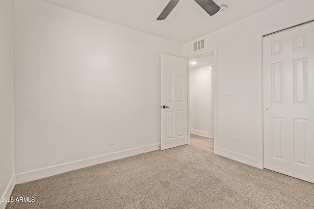 unfurnished bedroom featuring baseboards, visible vents, ceiling fan, and carpet