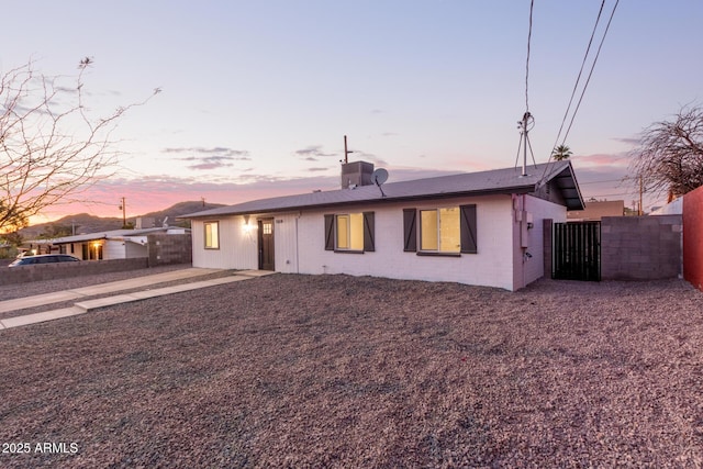 ranch-style home with fence and concrete block siding