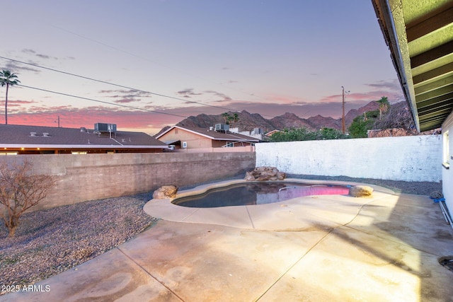 patio terrace at dusk with a fenced in pool and a fenced backyard