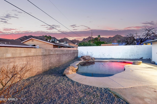 pool at dusk with a fenced in pool and a fenced backyard