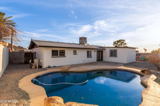 rear view of house with a fenced backyard, a fenced in pool, and a patio area