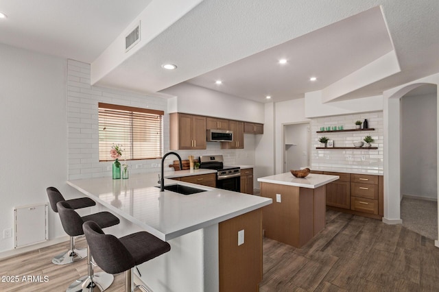 453 E Baylor Ln, Gilbert, AZ 85296 - kitchen with appliances with stainless steel finishes, a sink, open shelves, brown cabinets, and tasteful backsplash