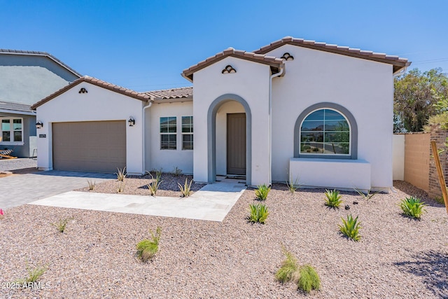 mediterranean / spanish-style home featuring stucco siding, an attached garage, driveway, and a tiled roof