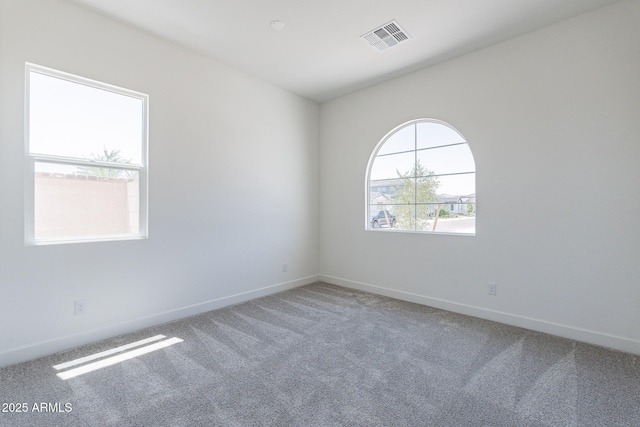 carpeted spare room with visible vents and baseboards