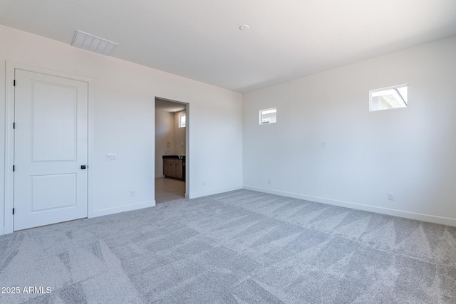 spare room featuring light colored carpet, visible vents, and baseboards