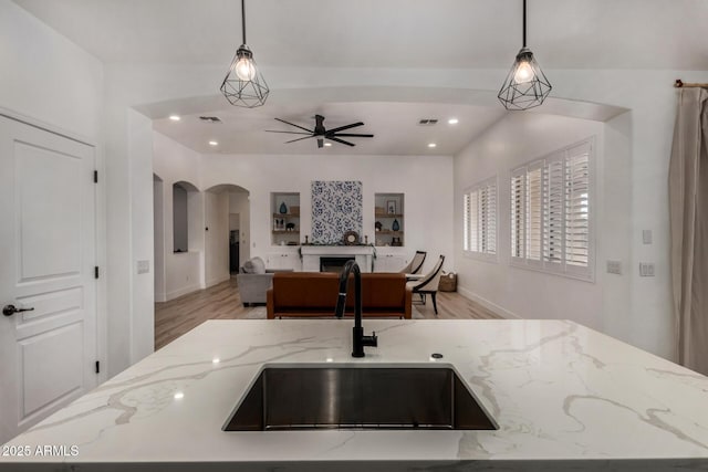 465 E Frances Ln, Gilbert, AZ 85295 - kitchen with arched walkways, a fireplace, ceiling fan, open floor plan, and pendant lighting