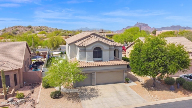mediterranean / spanish home featuring a tile roof, a garage, a mountain view, and driveway