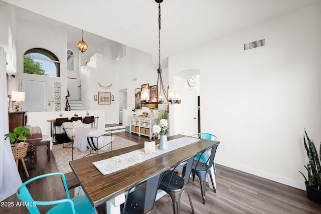 dining room featuring stairs, arched walkways, visible vents, a notable chandelier, and wood finished floors