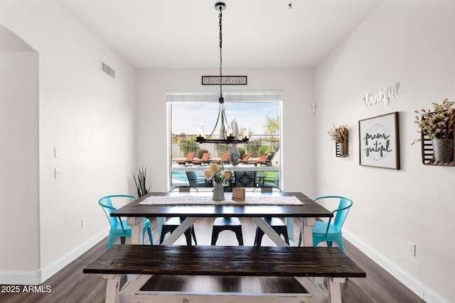 dining space featuring baseboards, a chandelier, arched walkways, visible vents, and wood finished floors