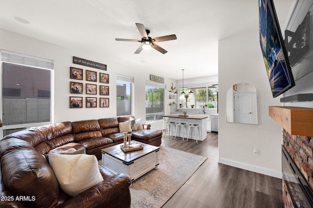 living room with a ceiling fan, dark wood-type flooring, baseboards, and a fireplace