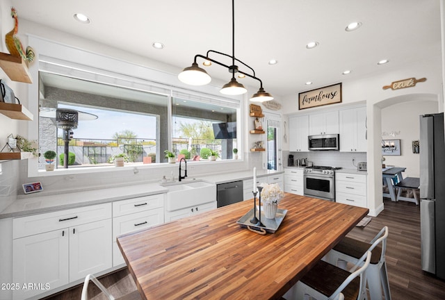 kitchen featuring stainless steel appliances, butcher block counters, white cabinetry, a sink, and open shelves