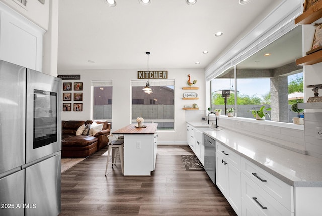kitchen with dark wood-style flooring, a sink, stainless steel appliances, and open shelves