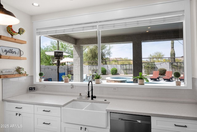 kitchen with white cabinets, a sink, open shelves, and stainless steel dishwasher