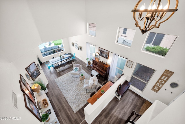living room featuring visible vents, a high ceiling, an inviting chandelier, and wood finished floors