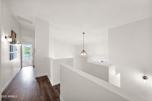 hall featuring an upstairs landing, lofted ceiling, baseboards, visible vents, and wood finished floors