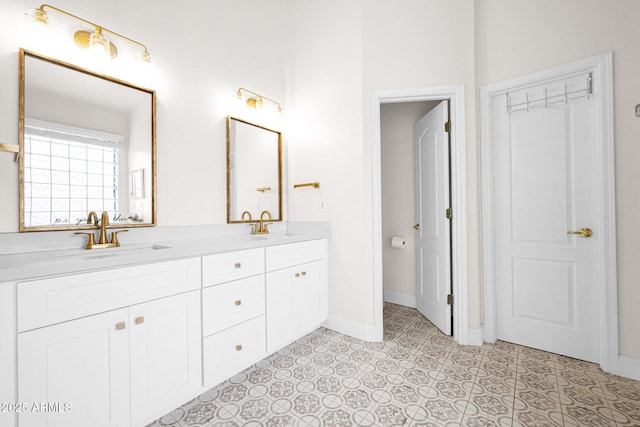 bathroom with double vanity, a sink, and baseboards