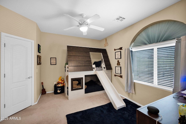 carpeted office with baseboards, visible vents, and a ceiling fan