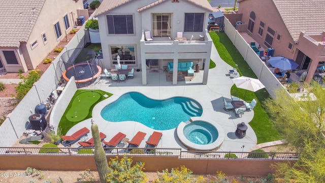 back of house with a pool with connected hot tub, a fenced backyard, outdoor dining space, stucco siding, and a patio area