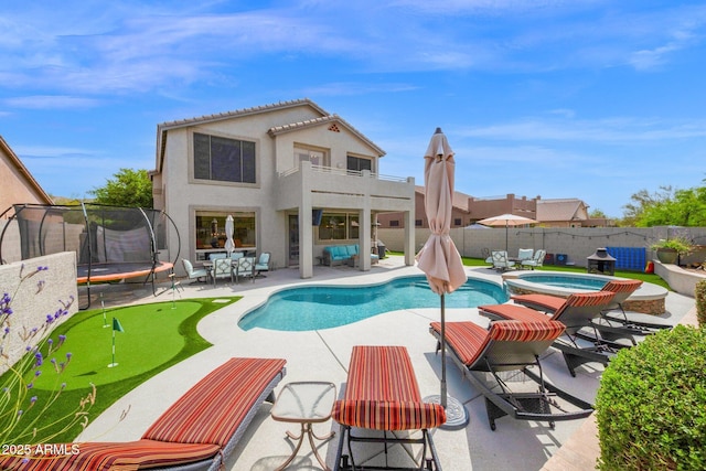 view of swimming pool featuring a fenced backyard, a pool with connected hot tub, a patio area, and a trampoline