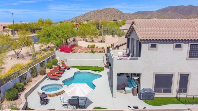 view of pool with a pool with connected hot tub, a fenced backyard, grilling area, a mountain view, and a patio area