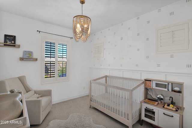 bedroom featuring a crib, light colored carpet, and a chandelier