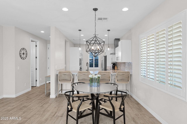 dining room with sink, light hardwood / wood-style flooring, and a notable chandelier