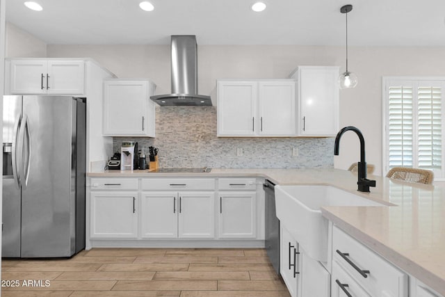 kitchen with white cabinetry, appliances with stainless steel finishes, decorative light fixtures, and wall chimney exhaust hood