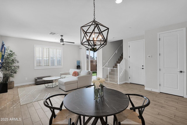 dining space featuring ceiling fan with notable chandelier and light hardwood / wood-style floors