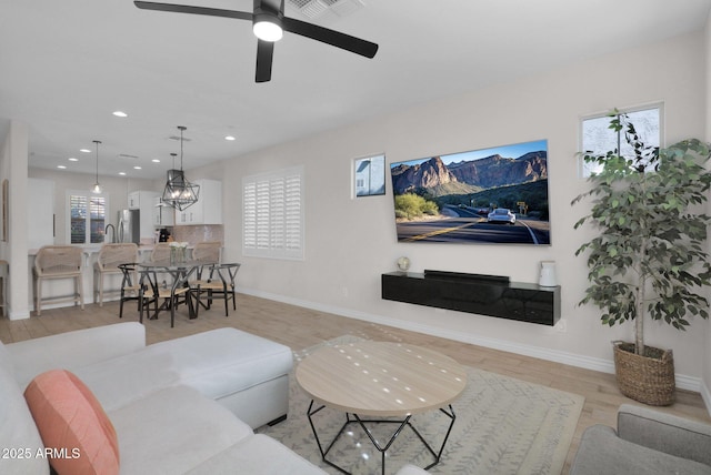 living room with ceiling fan and light hardwood / wood-style flooring