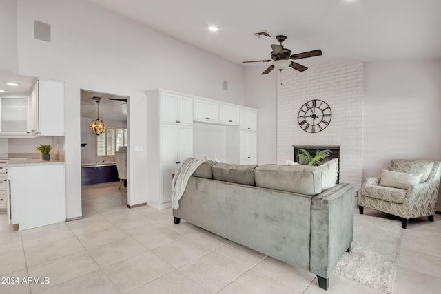 tiled living room with a fireplace, ceiling fan, and a high ceiling