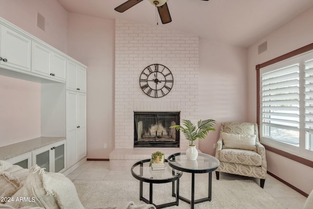 living room with lofted ceiling, a fireplace, ceiling fan, and light tile patterned flooring