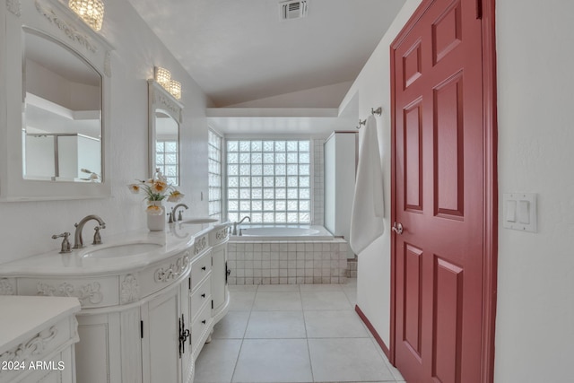 bathroom with a relaxing tiled tub, lofted ceiling, vanity, and tile patterned flooring