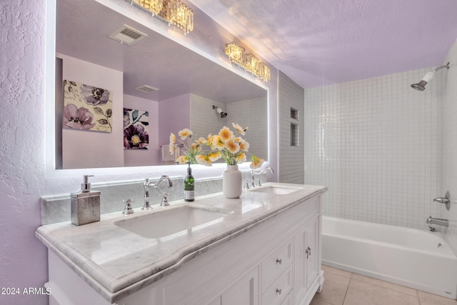 bathroom with tile patterned flooring, tiled shower / bath, vanity, and a textured ceiling