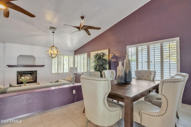 dining space featuring light tile patterned floors, a fireplace, vaulted ceiling, and a wealth of natural light