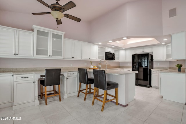 kitchen with a kitchen island, white cabinetry, a kitchen bar, a high ceiling, and black appliances