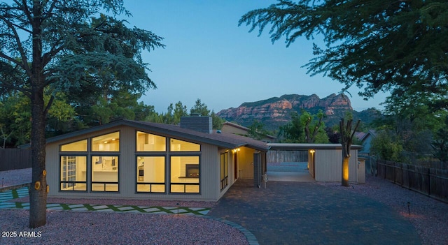 21 Hummingbird Cir, Sedona, AZ 86336 - back of property at dusk with a chimney, decorative driveway, and a mountain view