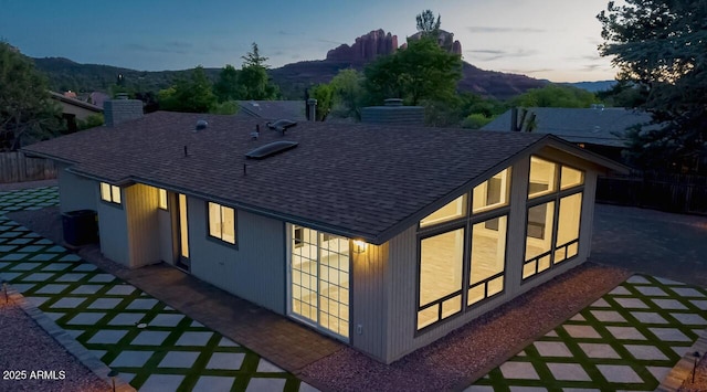 21 Hummingbird Cir, Sedona, AZ 86336 - property exterior at dusk featuring roof with shingles, a mountain view, and a chimney
