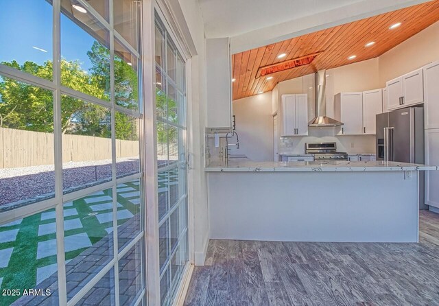 21 Hummingbird Cir, Sedona, AZ 86336 - kitchen featuring wall chimney exhaust hood, stainless steel appliances, wood ceiling, light stone countertops, and wood finished floors