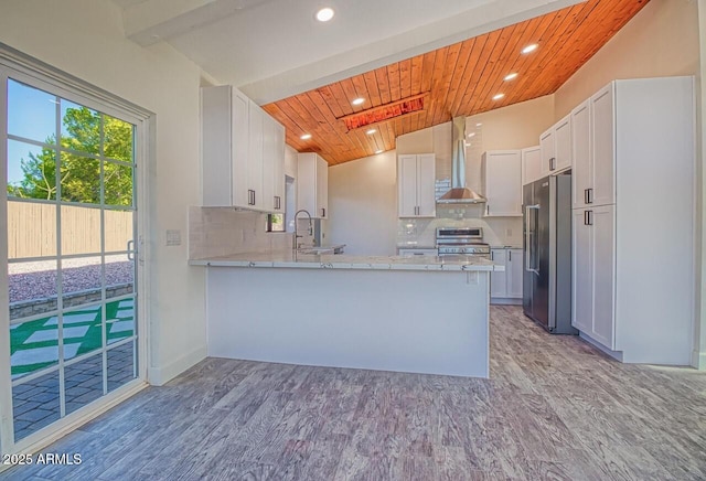 21 Hummingbird Cir, Sedona, AZ 86336 - kitchen featuring appliances with stainless steel finishes, wall chimney exhaust hood, a peninsula, light wood finished floors, and backsplash