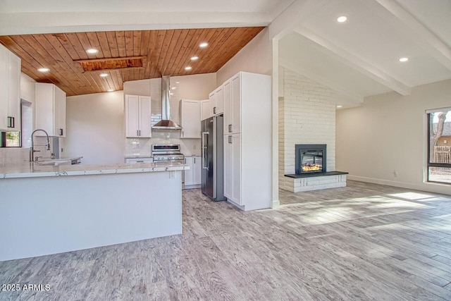 21 Hummingbird Cir, Sedona, AZ 86336 - kitchen with appliances with stainless steel finishes, light wood-style flooring, a peninsula, wall chimney range hood, and a sink